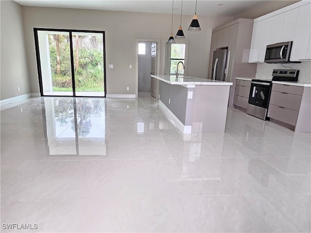 kitchen with stainless steel appliances, sink, decorative light fixtures, an island with sink, and white cabinets