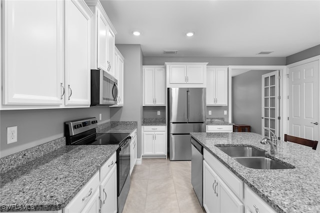 kitchen with white cabinets, stainless steel appliances, light stone counters, and sink