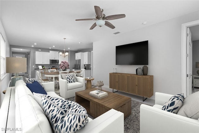 living room with ceiling fan with notable chandelier