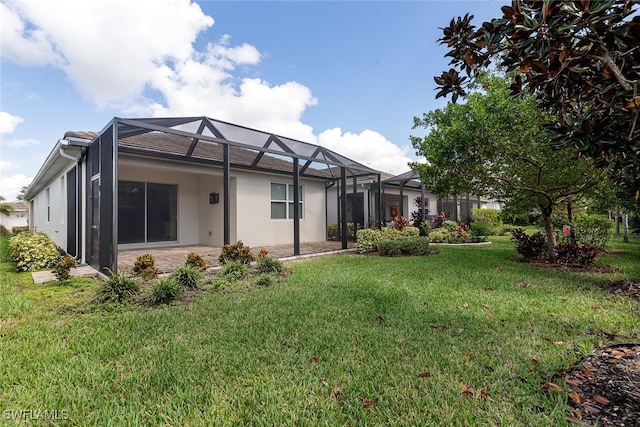 rear view of property with glass enclosure and a yard