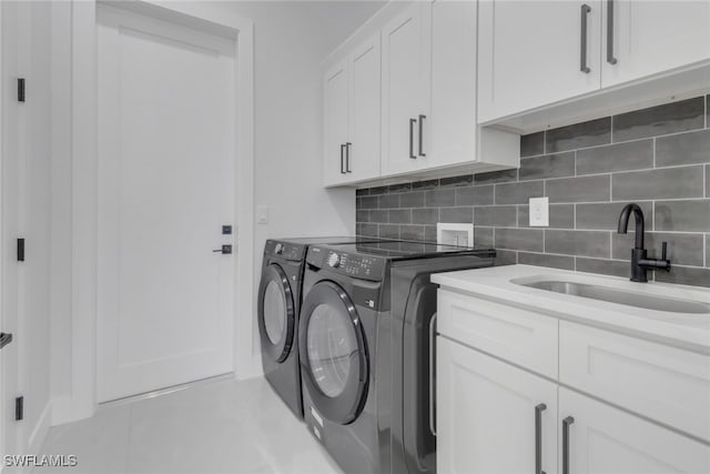 clothes washing area featuring cabinets, washer and dryer, light tile patterned floors, and sink