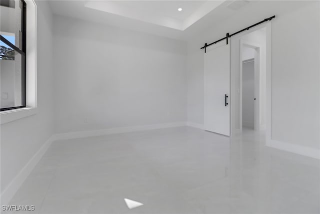 tiled empty room with a barn door and a tray ceiling