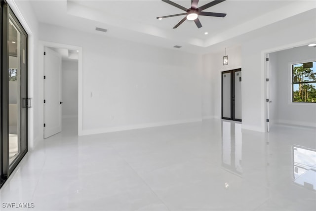 tiled spare room with a tray ceiling, french doors, and ceiling fan