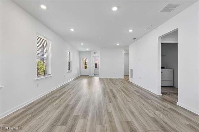 unfurnished living room featuring washer / clothes dryer and light hardwood / wood-style flooring