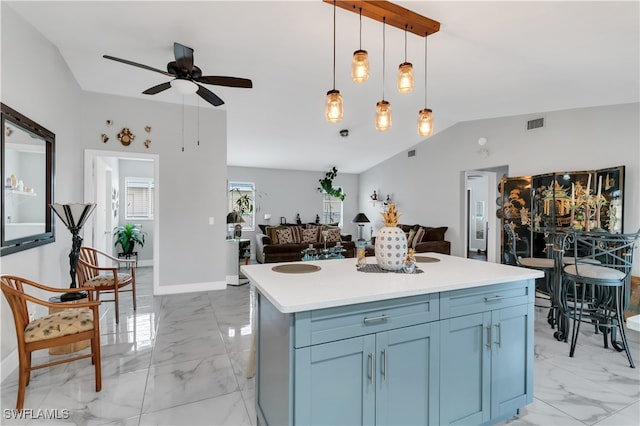 kitchen with blue cabinetry, ceiling fan, a center island, vaulted ceiling, and decorative light fixtures