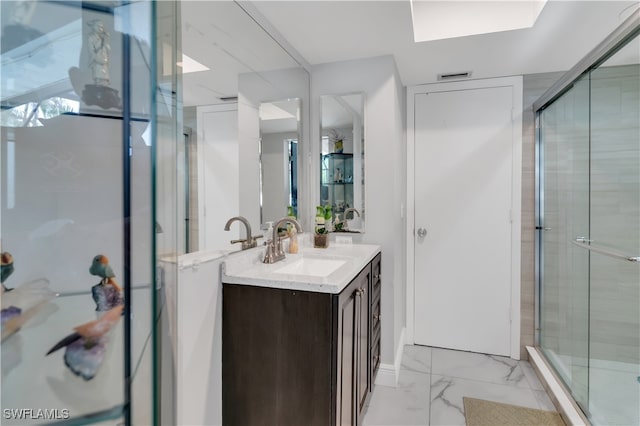 bathroom featuring a shower with door and vanity