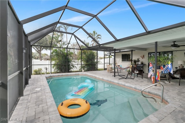 view of swimming pool with ceiling fan, a patio area, and glass enclosure