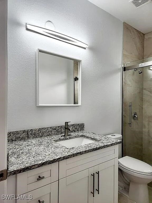 bathroom with toilet, vanity, and an enclosed shower