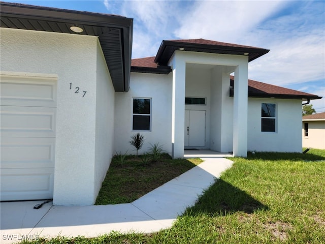 view of exterior entry with a garage and a yard