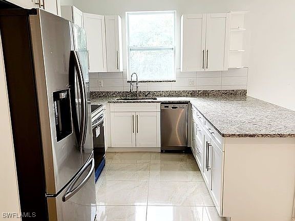 kitchen featuring stainless steel appliances, white cabinetry, and sink