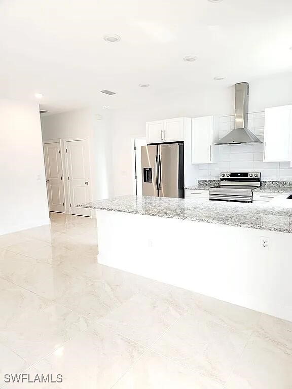 kitchen with white cabinets, light stone countertops, wall chimney exhaust hood, and appliances with stainless steel finishes