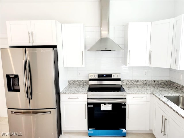 kitchen with white cabinetry, stainless steel appliances, wall chimney exhaust hood, and light stone counters