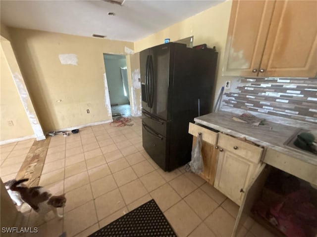 kitchen with black fridge, sink, light brown cabinets, light tile patterned floors, and backsplash