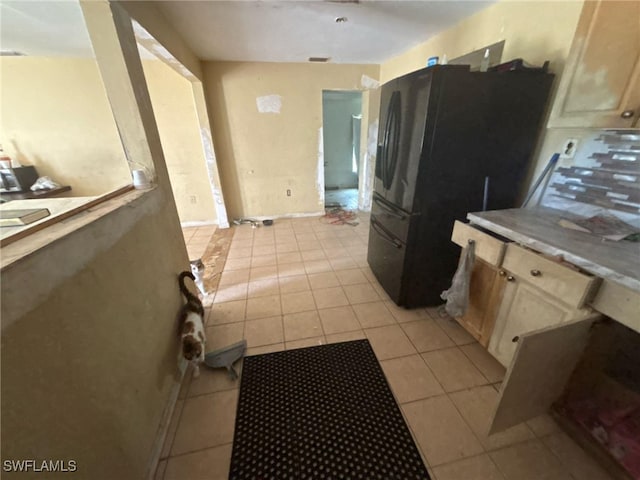 kitchen with black refrigerator and light tile patterned floors