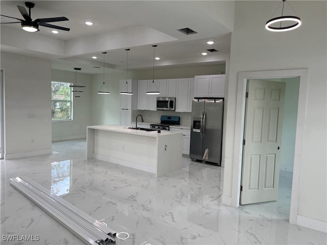 kitchen with a center island with sink, white cabinetry, appliances with stainless steel finishes, pendant lighting, and ceiling fan