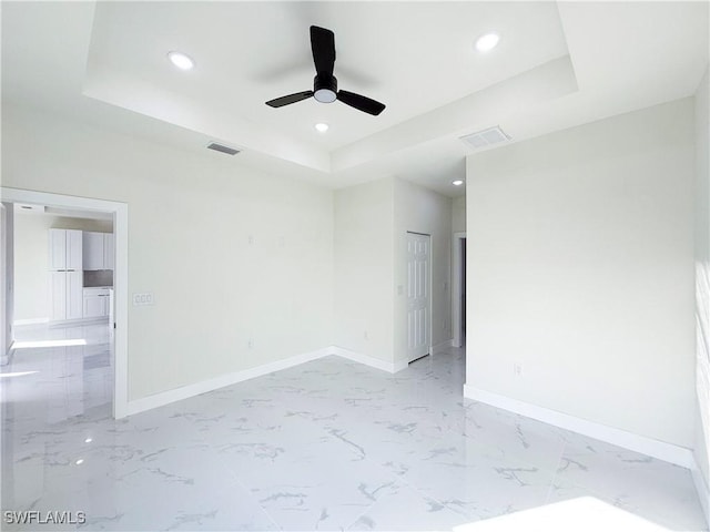 unfurnished room with ceiling fan and a raised ceiling