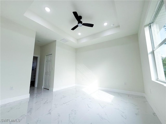 empty room with a raised ceiling and ceiling fan