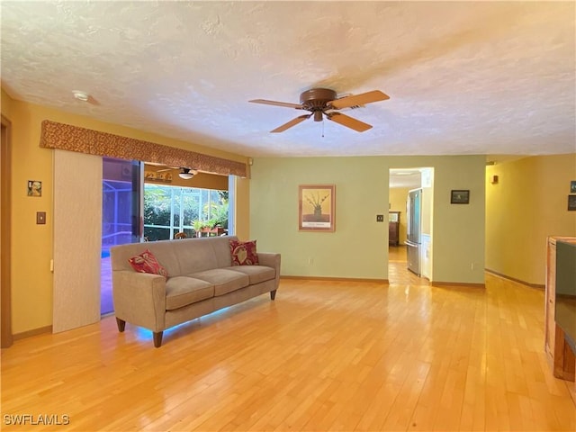 147 Pebble Beach Cir, Naples, FL 34113 - living room with light wood-style flooring, a ceiling fan, a textured ceiling, and baseboards