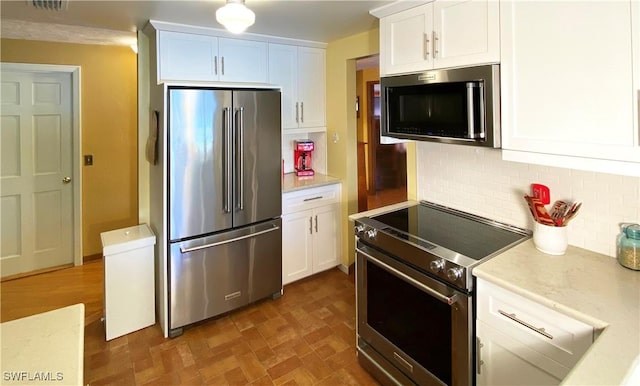 kitchen with white cabinets, backsplash, and stainless steel appliances