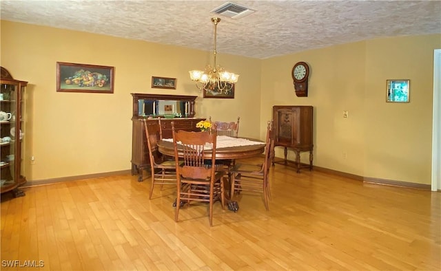 dining room featuring a chandelier, a textured ceiling, and light hardwood / wood-style floors