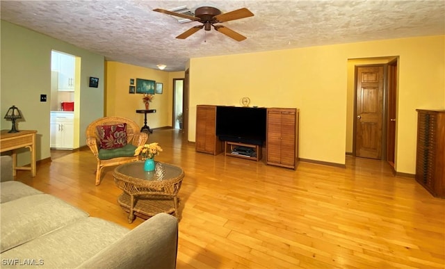 147 Pebble Beach Cir, Naples, FL 34113 - living room featuring light wood-style floors, ceiling fan, a textured ceiling, and baseboards