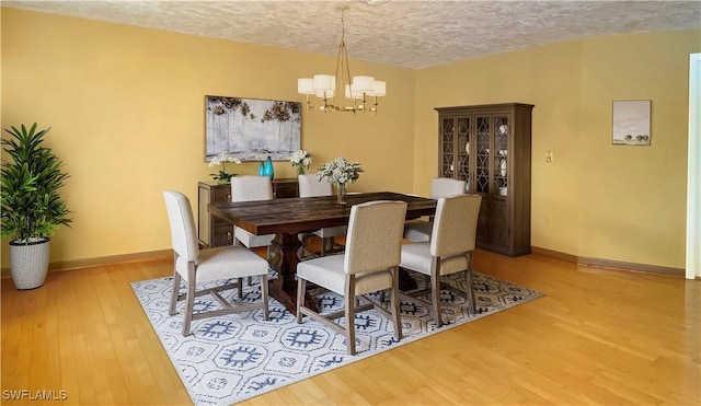 dining room with a chandelier, a textured ceiling, and light hardwood / wood-style floors