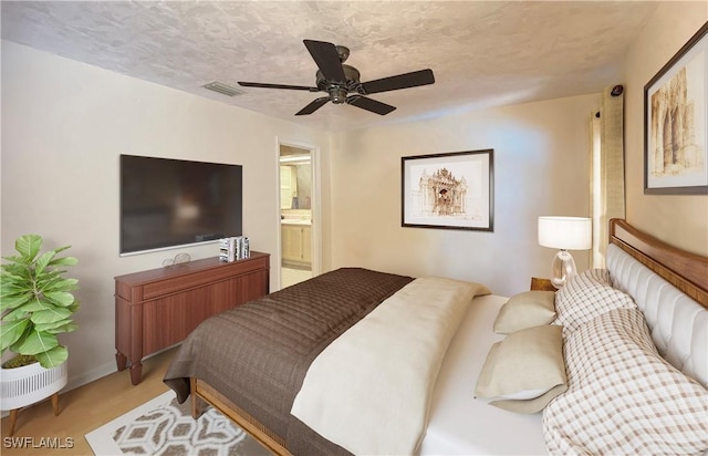 bedroom featuring a textured ceiling, connected bathroom, hardwood / wood-style flooring, and ceiling fan