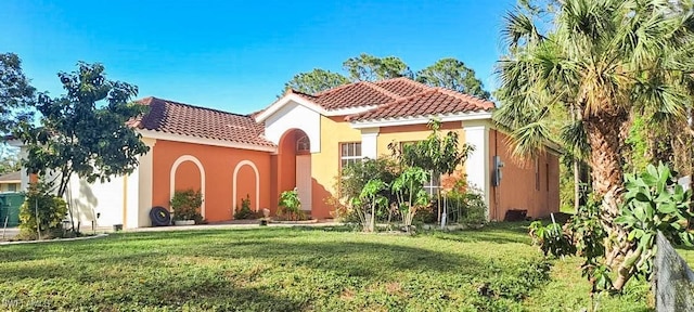 mediterranean / spanish house with a front yard, a tile roof, and stucco siding