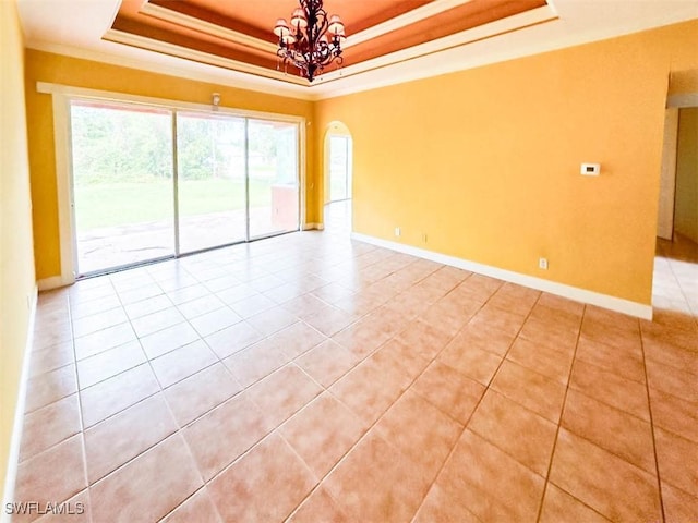 empty room featuring a raised ceiling, a chandelier, light tile patterned floors, baseboards, and crown molding