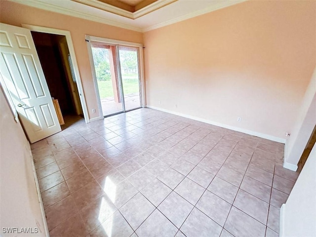 empty room featuring light tile patterned floors, a raised ceiling, ornamental molding, and baseboards