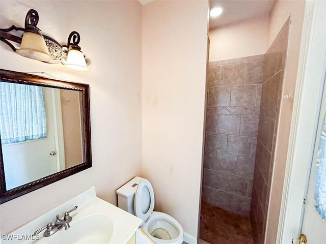 full bathroom featuring toilet, a tile shower, and vanity