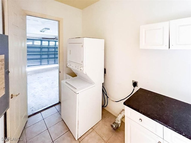 washroom featuring estacked washer and dryer, cabinet space, and light tile patterned floors