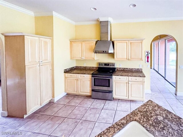 kitchen featuring stainless steel electric stove, wall chimney exhaust hood, arched walkways, crown molding, and light tile patterned floors