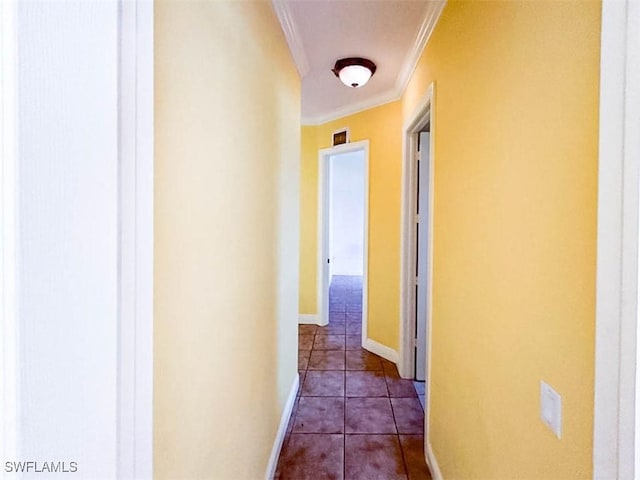 hall featuring crown molding, baseboards, and dark tile patterned floors