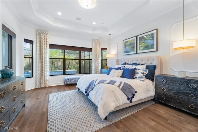 bedroom featuring hardwood / wood-style floors, a raised ceiling, and crown molding