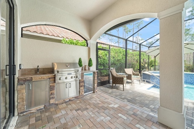 view of patio / terrace with glass enclosure, area for grilling, and an outdoor kitchen