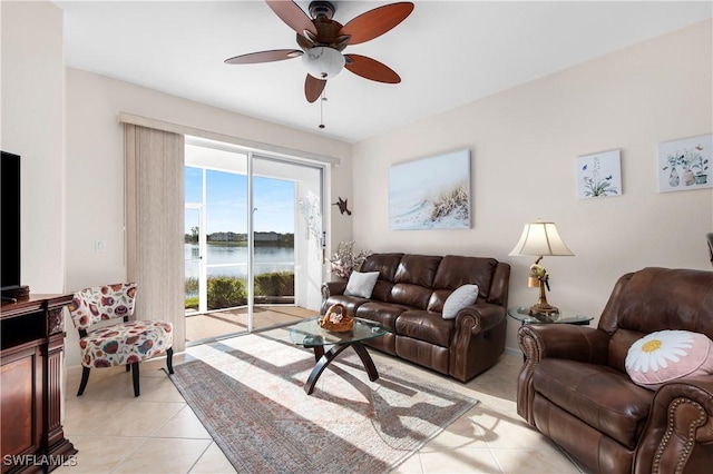 living area featuring a water view, ceiling fan, and light tile patterned floors