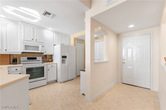 kitchen with white cabinets, white appliances, backsplash, and light tile patterned floors