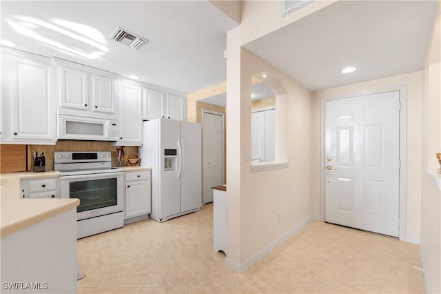 kitchen featuring light tile patterned floors, light countertops, visible vents, white cabinets, and white appliances