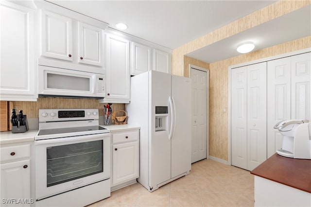 kitchen with white cabinets, light tile patterned floors, and white appliances