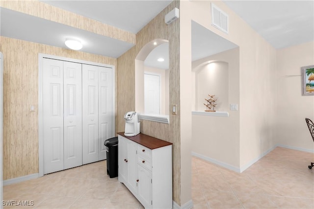 hallway featuring wallpapered walls, baseboards, visible vents, and light tile patterned flooring