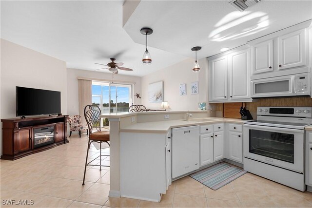 kitchen featuring white appliances, a kitchen breakfast bar, kitchen peninsula, decorative light fixtures, and white cabinetry