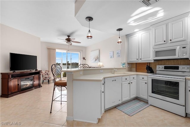 kitchen featuring white appliances, a peninsula, light countertops, a kitchen bar, and white cabinetry