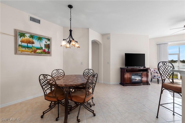 dining space with light tile patterned floors, baseboards, visible vents, and arched walkways