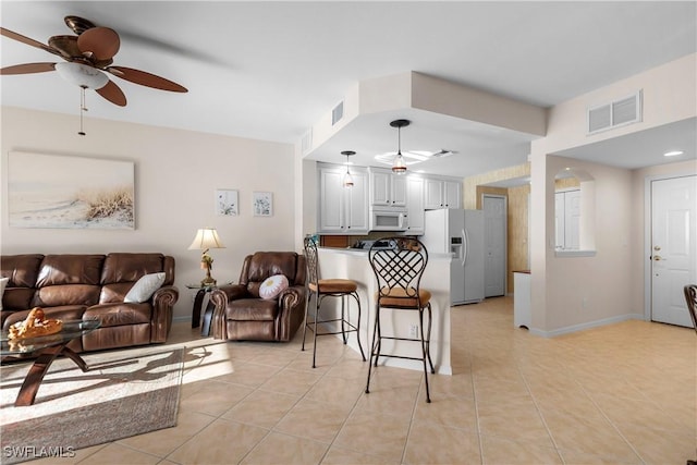 living room with a ceiling fan, visible vents, and light tile patterned flooring