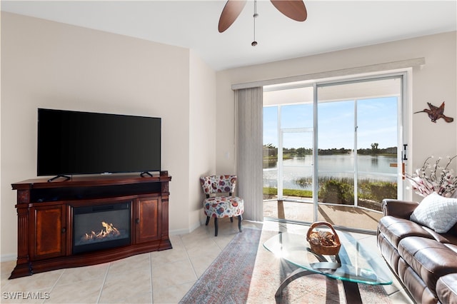 tiled living room with ceiling fan and a water view