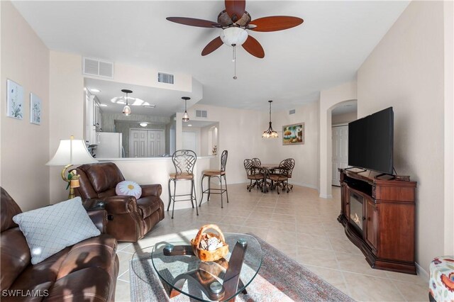 living area with arched walkways, light tile patterned flooring, and visible vents