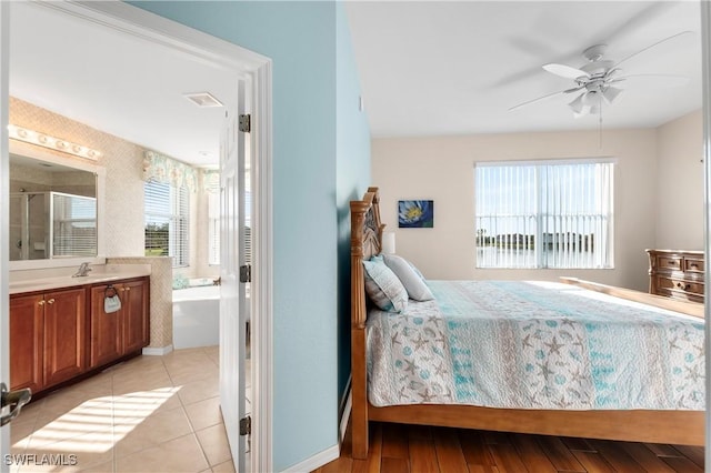 bedroom with light tile patterned floors, ensuite bath, ceiling fan, and a sink