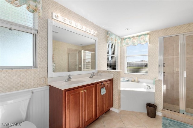 full bath featuring a wealth of natural light, a wainscoted wall, a sink, and wallpapered walls