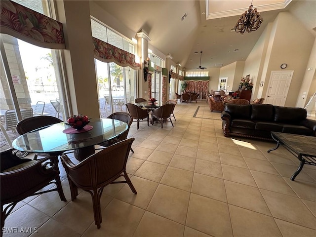 dining room with ceiling fan with notable chandelier, light tile patterned floors, crown molding, and high vaulted ceiling